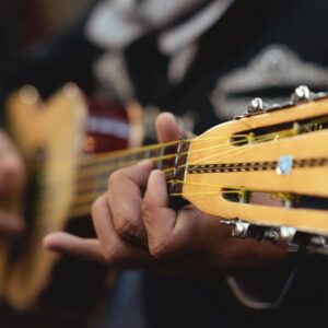 Detailed close-up of a mariachi musician playing a string guitar, showcasing skill and tradition.